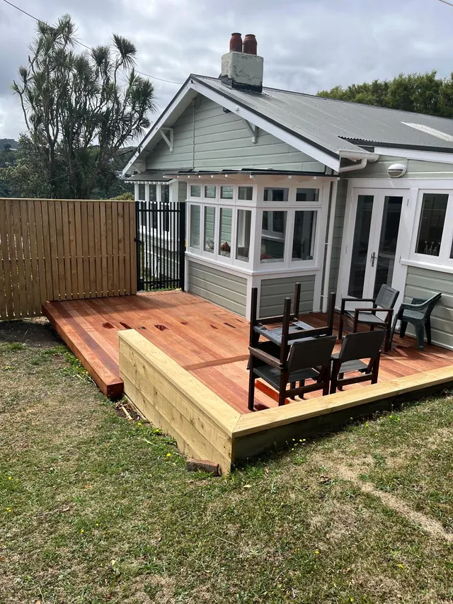 New timber deck with outdoor chairs beside a weatherboard house and fence