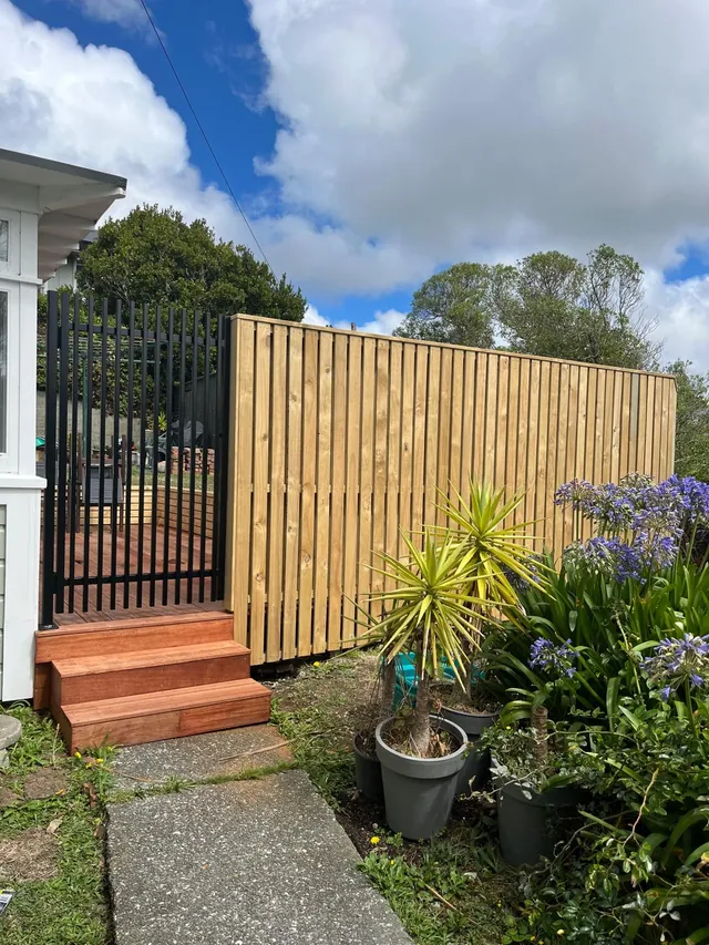 Vertical timber fence with a black gate and timber steps