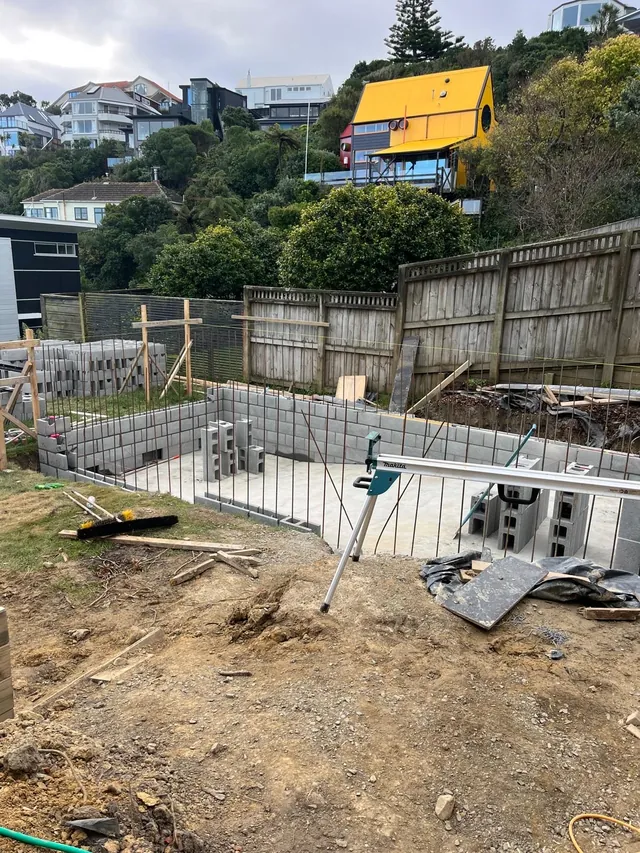 Concrete block pool walls part built, with steel starters in place