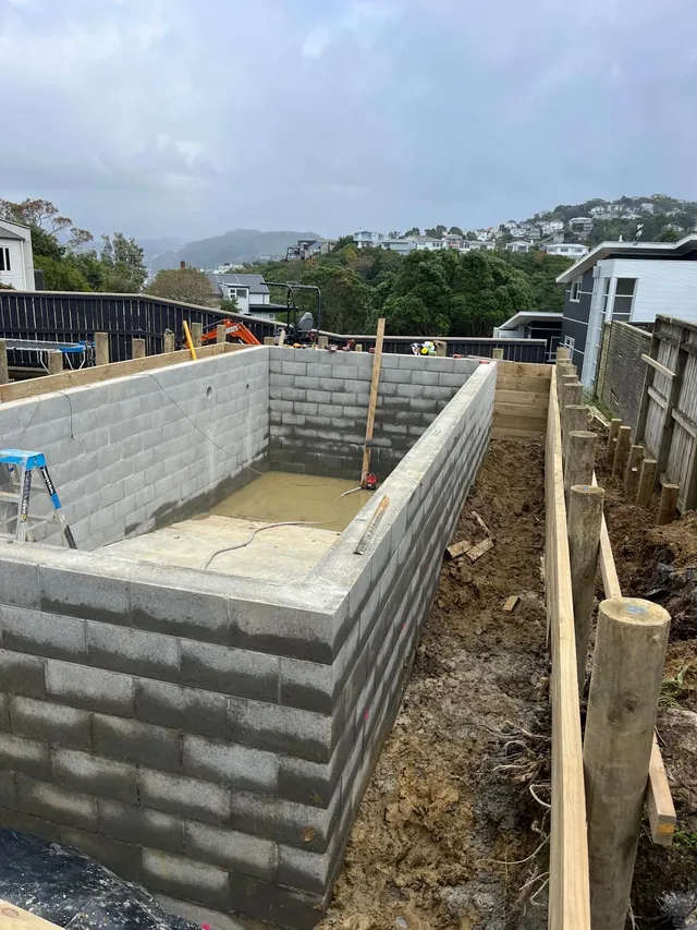 Concrete block pool walls built to full height beside a timber fence