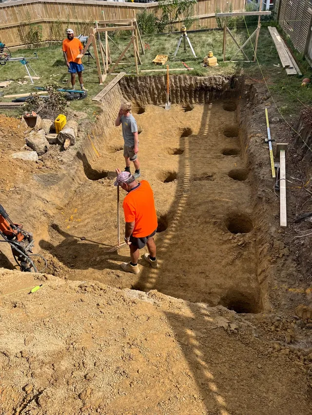 Builders digging out the pool, with holes cut into the base
