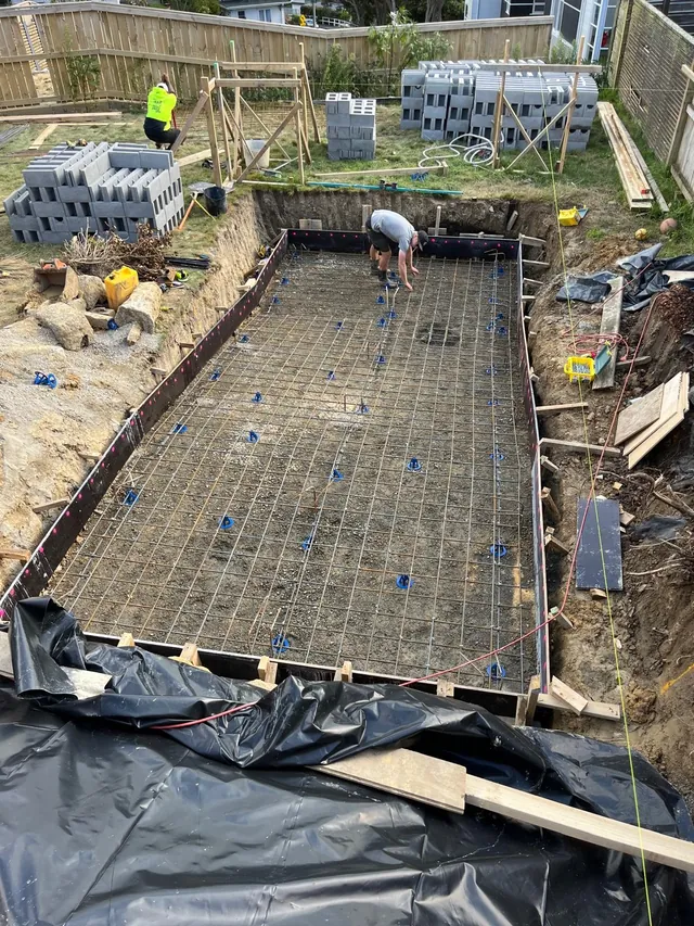 Steel reinforcing mesh laid in the base of the pool with blocks stacked nearby