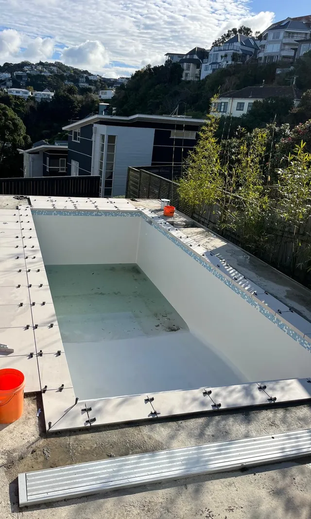 Pool shell with tiles being laid around the edge