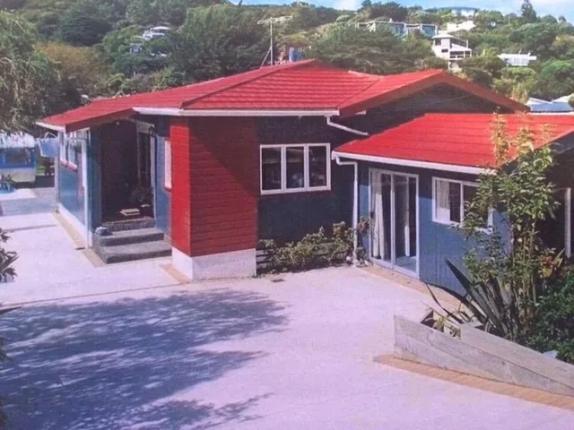 Before: photo of a printed photo of the house with a red roof and dark blue and red cladding, seen from the driveway