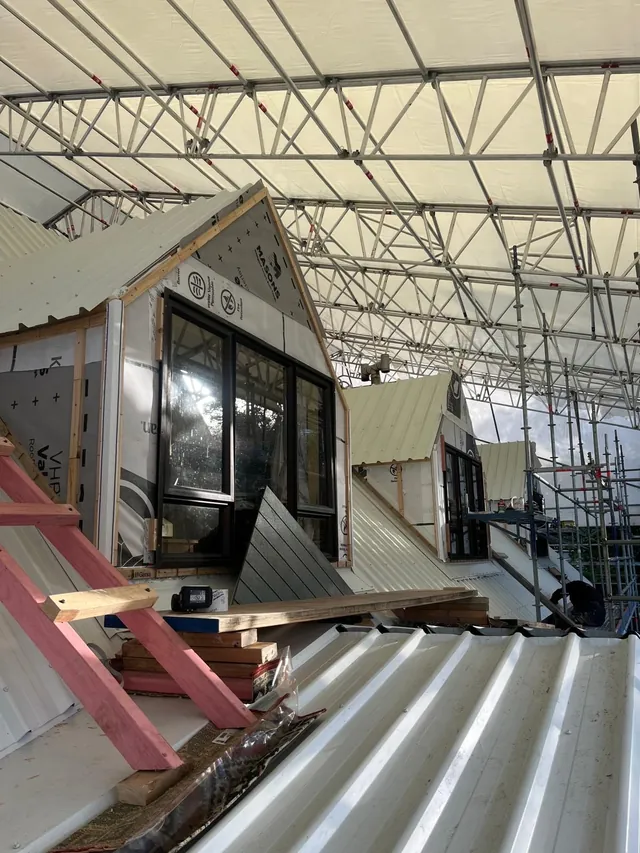 Row of new dormers along the roof under a scaffold cover, with roofing iron going on