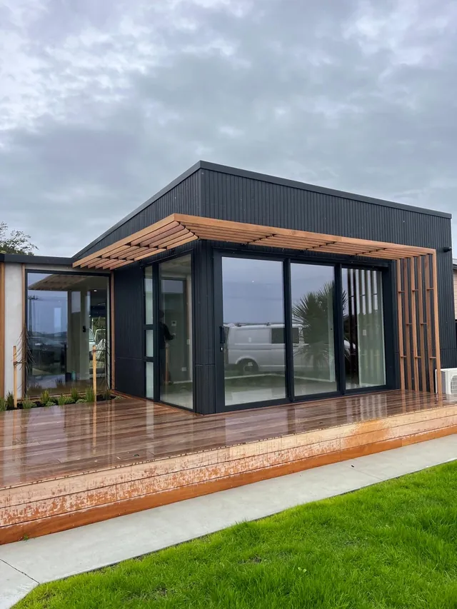 Timber battens over the glass doors and down the corner of a dark clad house