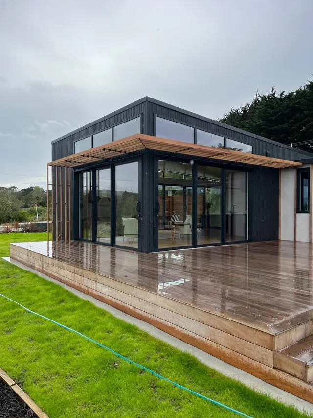 Timber batten screening above a run of glass doors on a dark clad house