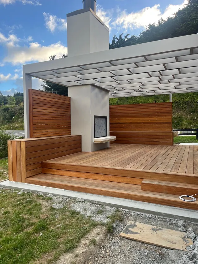 Horizontal timber screen walls around an outdoor fireplace under a white pergola